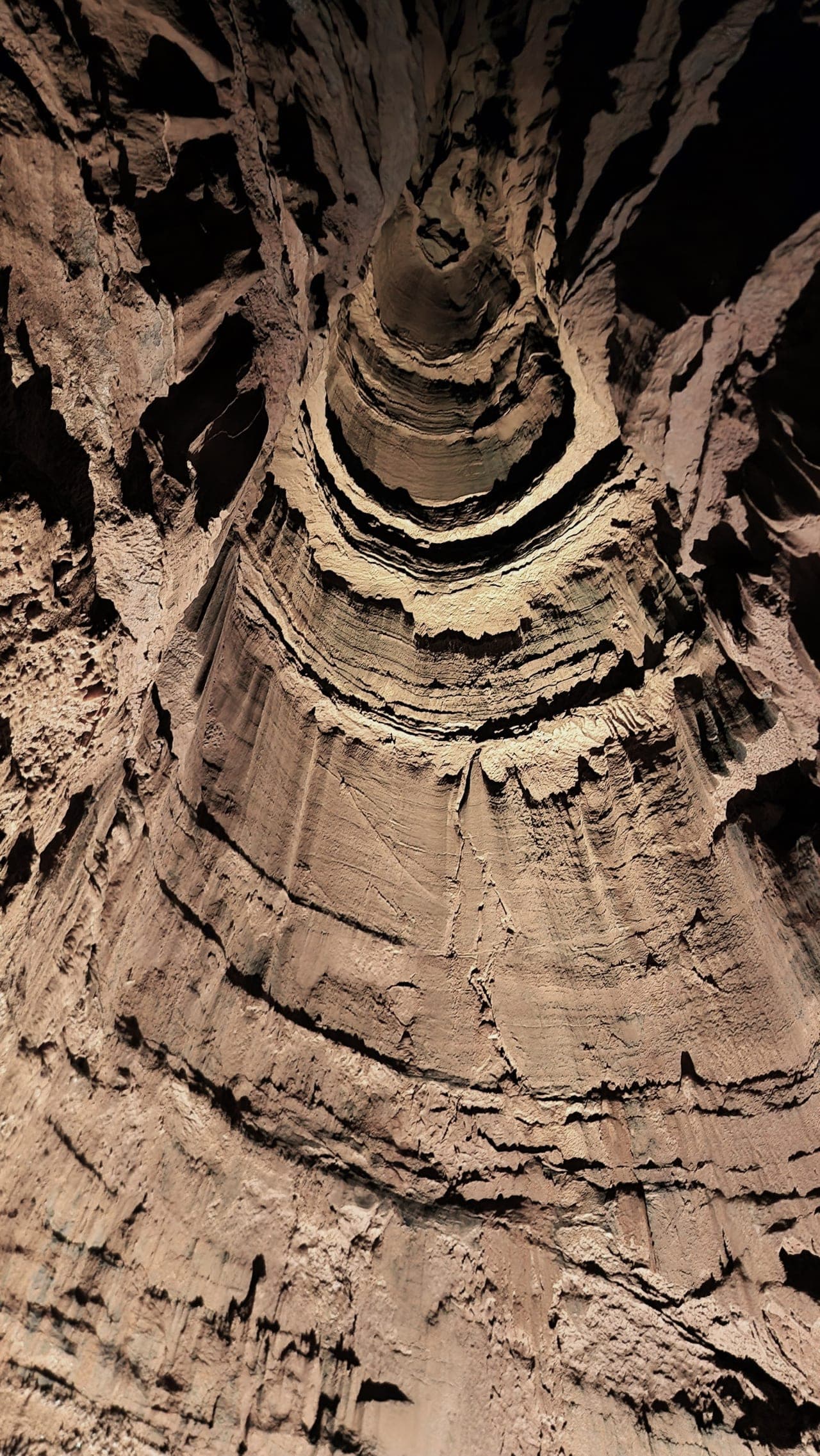 Vertical view up a cave dome with layered rock walls